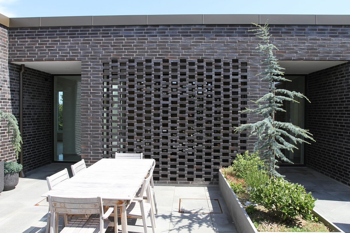 Terrasse med dekorativ muret gittervæg i mørke teglsten