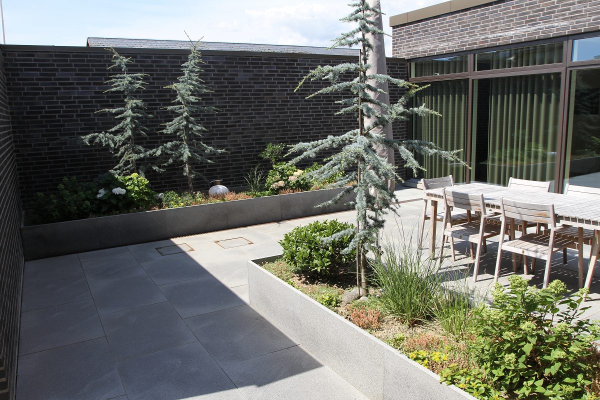 Stor flisebelagt terrasse ved hus i mørk tegl