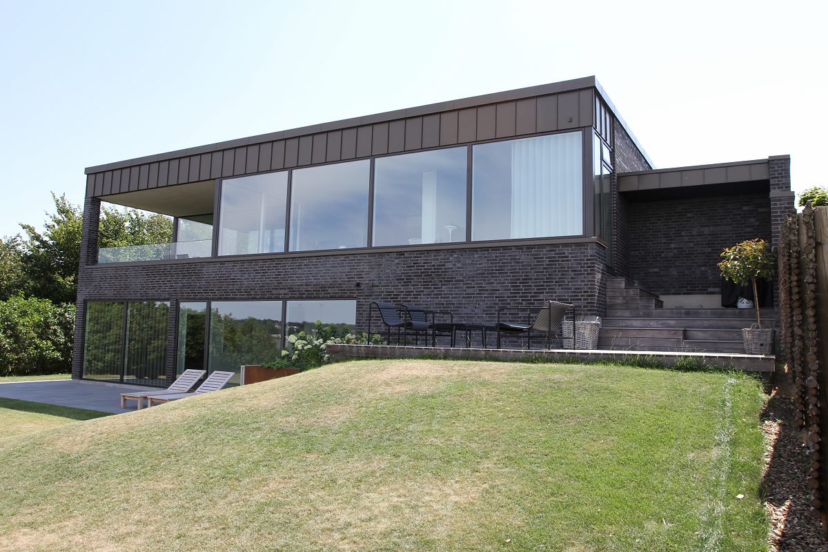 Moderne hus i to plan med gennemgående vinduesbånd og facade i mørk tegl