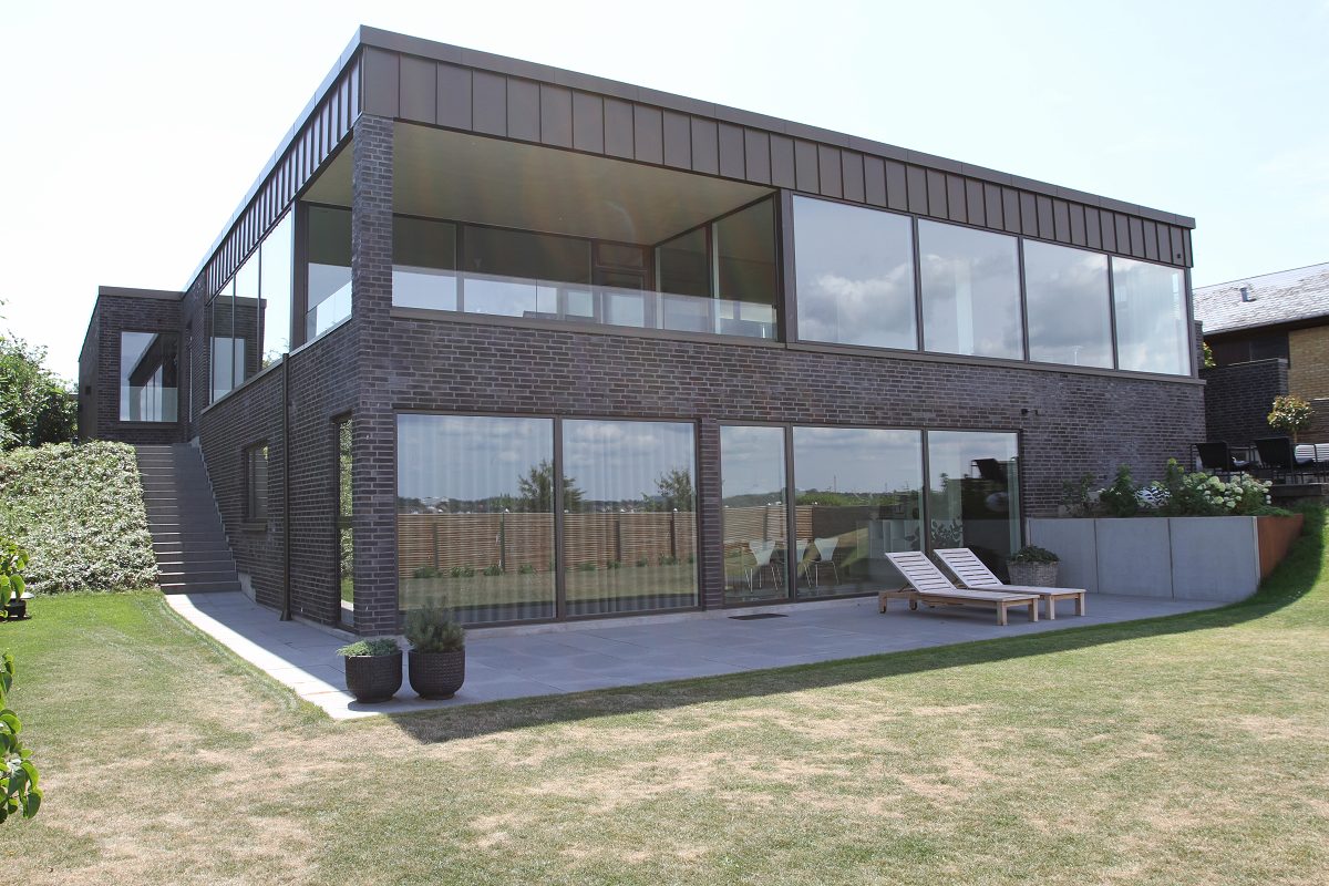 Villa i to plan med store glaspartier set fra haven
